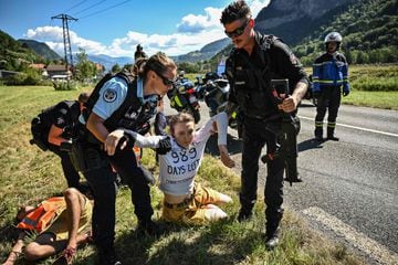 French gendarmes remove environmental protestors from the race route as their protest action temporarily immobilized the pack of riders during the 10th stage of the 109th edition of the Tour de France cycling race, 148,1 km between Morzine and Megeve, in the French Alps, on July 12, 2022. 