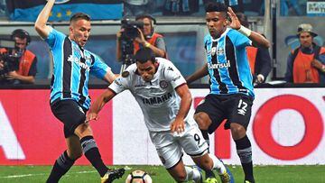 Arthur (L) and Cortez (R) of Brazilx92s Gremio, vie for the ball with Jose Sand of Argentina&#039;s Lanus, during their Copa Libertadores 2017 first leg final match at Arena Gremio stadium, in Porto Alegre, Brazil on November 22, 2017. / AFP PHOTO / NELSO