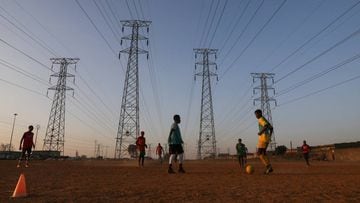 Men play soccer beneath Eskoms elecricity pylons, amid a nationwide coronavirus disease (COVID-19) lockdown in Soweto, south-west of Johannesburg, South Africa August 20, 2020. REUTERS/Siphiwe Sibeko