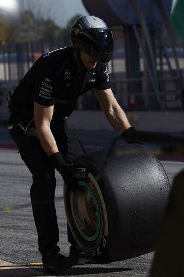A Mercedes mechanic wheels a tyre.