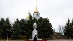 A man walks past a monument to the Soviet state founder Vladimir Lenin and an Orthodox church at a settlement in the southern Russian Rostov region on February 25, 2022.