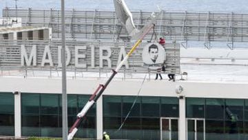 Workers add a sign bearing Cristiano Ronaldo's face to the airport exterior ahead of its 29 March name change to Madeira Cristiano Ronaldo Airport.