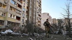 A member of the Ukrainian Territorial Defence Forces walks near a damaged apartment block after it was hit by debris from a downed rocket in Kyiv on March 17, 2022, as Russian forces press in on the Ukrainian capital.