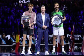 Jannik Sinner (a la izquierda con el título de campeón del Open de Australia), Daniil Medvedev (a la derecha con el título de subcampeón) posan junto al extenista Jim Courier.