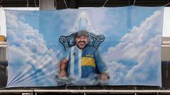(FILES) In this file photo taken on March 14, 2021 a banner with an image of late Argentine football icon Diego Maradona is seen during the Argentine Professional Football League Superclasico match between Boca Juniors and River Plate at La Bombonera stadium in Buenos Aires. - The public prosecutor&#039;s office investigating Argentine football star Diego Maradona&#039;s death postponed on May 28, 2021 for June 14 the beginning of the hearings of seven people suspicious of having &quot;abandoned him to his fate&quot;, which were scheduled to start on May 31. (Photo by Alejandro PAGNI / POOL / AFP)