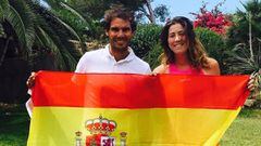 Los tenistas Rafa Nadal con Garbi&ntilde;e Muguruza sujetando una bandera de Espa&ntilde;a en un jard&iacute;n.