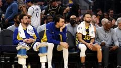 Klay Thompson #11, Dario Saric #20 and Stephen Curry #30 of the Golden State Warriors sit on the bench during the closing minutes of their loss to the Miami Heat in the second half at Chase Center on December 28, 2023 in San Francisco, California.
