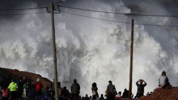Gente mirando desde el acantilado cómo rompe una ola gigante en Praia do Norte, Nazaré (Portugal) el 25 de febrero del 2022.