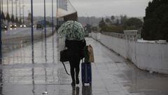 una persona camina bajo la lluvia con un paraguas y una maleta. En Sevilla (Andaluc&iacute;a, Espa&ntilde;a), a 04 de diciembre de 2020.