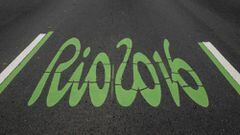 The logo of the Rio 2016 Olympic Games painted in green to distinguish it as the special lane for the games, on a road pedestrianized on Sundays, on June 26, 2016, in Rio de Janeiro, Brazil. / AFP PHOTO / YASUYOSHI CHIBA