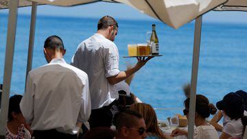 Waiters server drinks to customers at the terrace of restaurant on a hot summer day in Malaga, Spain, July 9, 2022. REUTERS/Jon Nazca