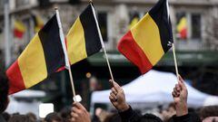 People wave Belgian flags as they observe a minute of silence