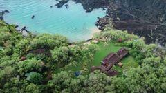 La mansi&oacute;n de Jeff Bezos en Maui, Haw&aacute;i, vista desde el aire, con la playa de aguas cristalinas, &aacute;rboles, palmeras y el r&iacute;o de lava. 