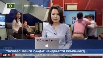 In Mongolia; A man unsuccessfully attempts to break up a fight between two employees while this unsuspecting news reporter is just trying to do her job.
