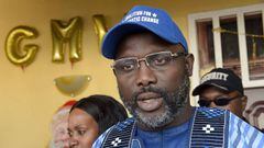 Liberian presidential candidate and ex-football international George Weah (R) speaks flanked by his wife Clar (L)   outside their house in Monrovia on December 23, 2017.
