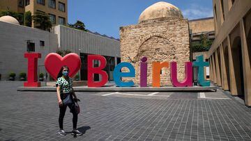 A woman wearing a face mask walks past an &quot;I love Beirut&quot; sign, near a shopping district, as Lebanon imposed a partial lockdown for two weeks starting on Friday in an effort to counter the spread of the coronavirus disease (COVID-19), which have