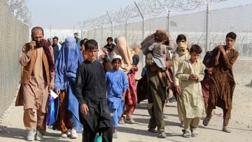 Afghan people walk inside a fenced corridor as they enter Pakistan at the Pakistan-Afghanistan border crossing point in Chaman on August 25, 2021 following the Taliban&#039;s stunning military takeover of Afghanistan.