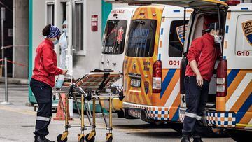 A member of an ambulance crew sanitises a gurney at the emergencies of the Greenacres Hospital in Port Elizabeth, on July 10, 2020 near a line of queuing ambulances. - Ambulances have to queue before patients suspected of having symptoms related to the CO