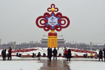 24 January 2022, China, Beijing: A group of people stand in front of a decoration for the 2022 Beijing Winter Olympics on display in Tiananmen Square. The Beijing Winter Olympics will take place from 04 to 20 February.