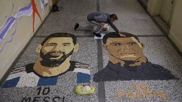 Kosovar artist Alkent Pozhegu works on the last details of his mosaic, made with grain and seeds on the ground, depicting Argentina's soccer player Lionel Messi and France's soccer player Kylian Mbappe in Gjakova, Kosovo, December 18, 2022. REUTERS/Fatos Bytyci