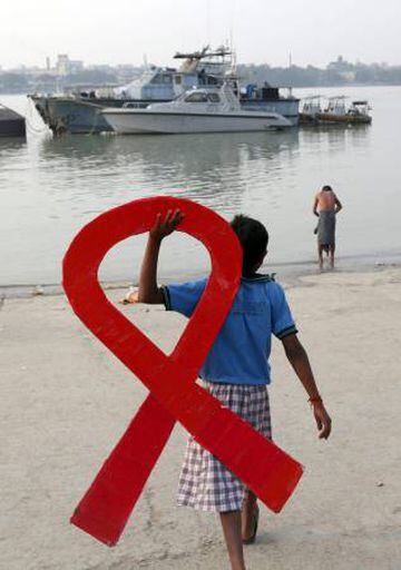 Un niño sostiene un lazo rojo que hace referencia al virus del sida durante el Día Mundial de esta enfermedad en Calcuta, la India.