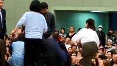 Unas mujeres entran a un ring de sumo para ateneder al alcalde de Maizuru, Ryozo Tatami, tras sufrir un colapso.