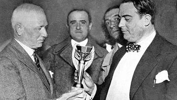 Jules Rimet (izquierda), presidente de la FIFA, entrega el trofeo de la Copa del Mundo a Ra&uacute;l Jude, presidente de la Federaci&oacute;n Uruguaya, antes de la celebraci&oacute;n de la primera edici&oacute;n del torneo en 1930.