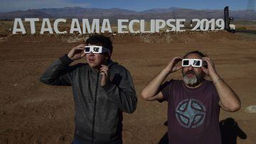 Tourists look at the sun before a solar eclipse in a entrance of an astronomical camp which expects to receive thousands of tourists to observe the July 2 total solar eclipse, in the commune of Vallenar in the Atacama desert about 600 km north of Santiago, on July 1, 2019. - A total solar eclipse will be visible from small parts of Chile and Argentina on July 2. (Photo by MARTIN BERNETTI / AFP)