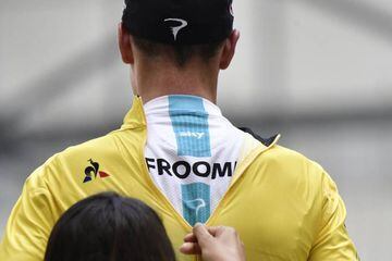 A hostess zips up the overall leader yellow jersey on Great Britain's Christopher Froome.