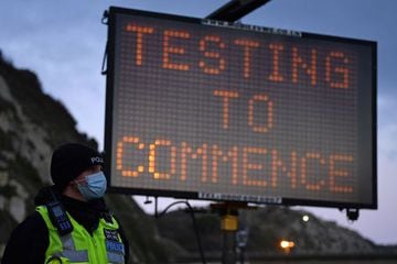 Police officers stand on duty at beneath a sign reading "Testing to Commence", at the entrance to the Port of Dover in Kent, south east England, on December 23, 2020.