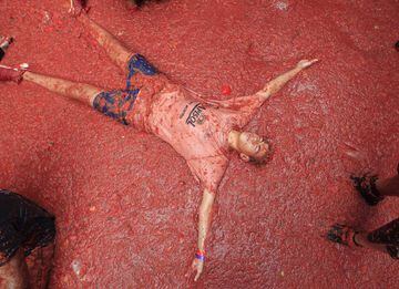 A men lies in a puddle of squashed tomatoes during the annual "Tomatina", tomato fight fiesta, in the village of Bunol, 50 kilometers outside Valencia, Spain, Wednesday, Aug. 30, 2017. The streets of an eastern Spanish town are awash with red pulp as thousands of people pelt each other with tomatoes in the annual "Tomatina" battle that has become a major tourist attraction. At the annual fiesta in Bunol on Wednesday, trucks dumped 160 tons of tomatoes for some 20,000 participants, many from abroad, to throw during the hour-long morning festivities. (AP Photo/Alberto Saiz)