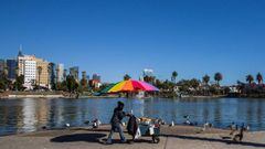 A street vendor pushes her cart in MacArthur Park, Los Angeles on May 21, 2020. - Undocumented immigrants impacted by the corornavirus shutdown can apply for California coronavirus emergency assistance plan for undocumented people put in place by Governor