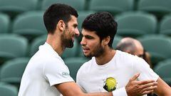 Serbia's Novak Djokovic (L) shakes hands with Spain's Carlos Alcaraz during a practise session prior to their men's singles semi-finals tennis matches on the twelfth day of the 2023 Wimbledon Championships at The All England Lawn Tennis Club in Wimbledon, southwest London, on July 14, 2023. (Photo by SEBASTIEN BOZON / AFP) / RESTRICTED TO EDITORIAL USE