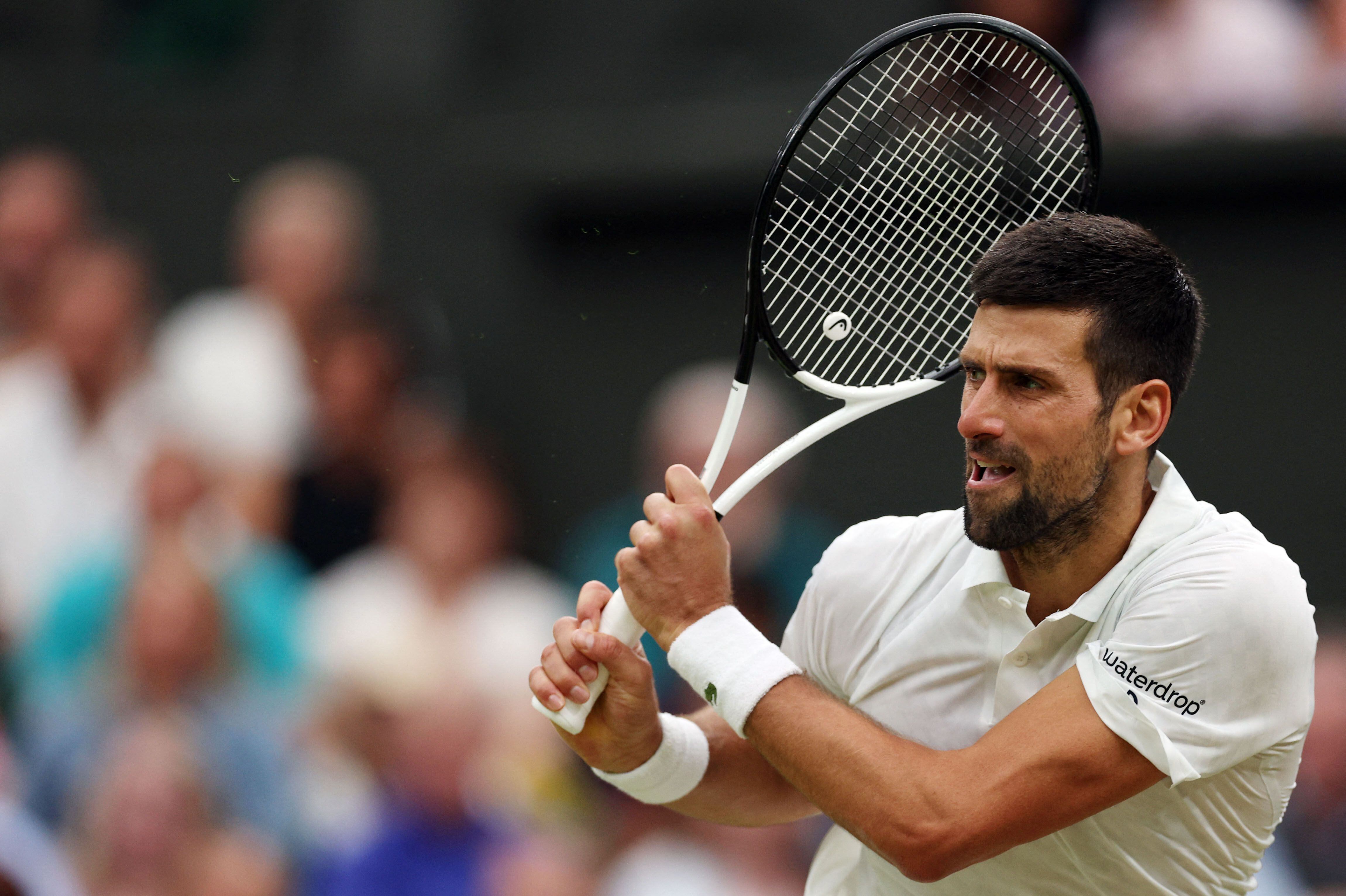 Serbia's Novak Djokovic returns the ball to Italy's Jannik Sinner during their men's singles semi-finals tennis match on the twelfth day of the 2023 Wimbledon Championships at The All England Lawn Tennis Club in Wimbledon, southwest London, on July 14, 2023. (Photo by Adrian DENNIS / AFP) / RESTRICTED TO EDITORIAL USE