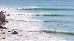 Cuatro olas rompiendo una tras otra en Cantabria, al lado de unos acantilados, con un surfista en cada una, en noviembre del 2022. 