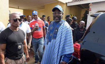 Liberian presidential candidate and ex-football international George Weah (C) walks flanekd by security personnel outside his house in Monrovia on December 23, 2017.