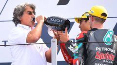 Paolo Simoncelli (L), the father of Italian late motorbike racer Marco Simoncelli, drinks champagne as he joins second-placed Petronas Sprinta Racing British rider, John Mcphee (R) and race winner SIC58 Squadra Corse Japanese rider, Tatsuki Suzuki as they