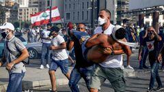 A Lebanese protester carries a wounded demonstrator away from clashes in downtown Beirut on August 8, 2020, following a demonstration against a political leadership they blame for a monster explosion that killed more than 150 people and disfigured the cap