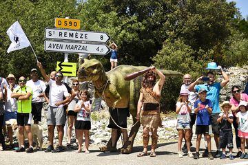 Un espectador disfrazado de hombre prehistórico y otro vestido como un dinosaurio anuncian una visita turística a la cueva de Aven Marzal.