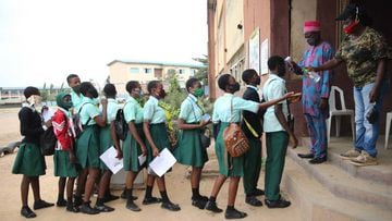 Students stay in line for a temperature check by teachers at Babs Fafunwa Millennium Senior Secondary students in Ojodu district in Lagos, Nigeria. 