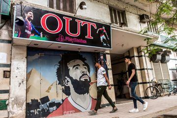 Jóvenes egipcios llegan al cibercafé de PlayStation en el centro de El Cairo con su entrada decorada con imágenes de Mohamed Salah, junto al delantero argentino Lionel Messi y el portugués del Real Madrid, Cristiano Ronaldo