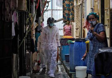 A worker from Bharatiya Jain Sanghatana, a non-governmental organization, wearing a "Smart Helmet", a portable thermoscanner that can measure the temperature of people at a distance, walks in an alley to screen the residents in a slum Mumbai, India.