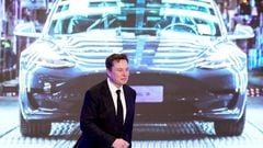 Tesla Inc CEO Elon Musk walks next to a screen showing an image of Tesla Model 3 car.