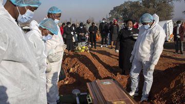 Johannesburg (South Africa), 24/07/2020.- Family members wearing full PPE suites as they stand at the graveside of an elderly family member who died as a result of the elderly Covid-19 Coronavirus at a graveyard on the 119 day of lockdown due to the Covid