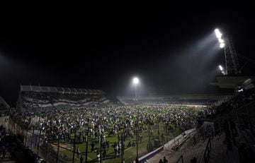 Fans of Gimnasia y Esgrima La Plata affected by tear gas invade the pitch during the match between Gimnasia and Boca Juniors at the Juan Carmelo Zerillo Stadium in La Plata, Argentina on October 6, 2022.