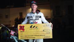 El piloto de MTB Juanfer Mu&ntilde;oz mostrando el cheque de la victoria en el Ultimate Urban Enduro de Guanajuato (M&eacute;xico), el 12 de noviembre del 2022, frente a su bici. 