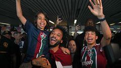 Brazilian defender Marcelo, wrapped in a flag of Brazilian team Fluminense, cheers at fans with his wife Clarise Alves and their sons Enzo (R) and Liam, upon arriving at Galeao Airport in Rio de Janeiro, Brazil, on March 9, 2023, on the eve of his official presentation. - Marcelo, five-time European champion with Real Madrid, signed with Fluminense until December 2024. (Photo by Carl DE SOUZA / AFP)