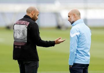 Manchester City manager Pep Guardiola speaks to former footballer Thierry Henry.