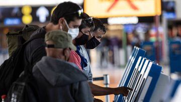 Passengers wear face masks while printing their boarding pass at Santiago International Airport, in Santiago, on April 20, 2020 during the new coronavirus, COVID-19, pandemic. - Latin America&#039;s biggest airline, the Brazilian-Chilean group LATAM, announced last Friday that the 95% reduction of its passenger operations announced in April will be extended until May due to the coronavirus crisis, which will cause a deeper impact than expected. (Photo by MARTIN BERNETTI / AFP)