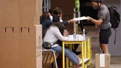 Jornada electoral. Mesa de votación en Colombia con jurados y elector recibe su tarjetón para votar.